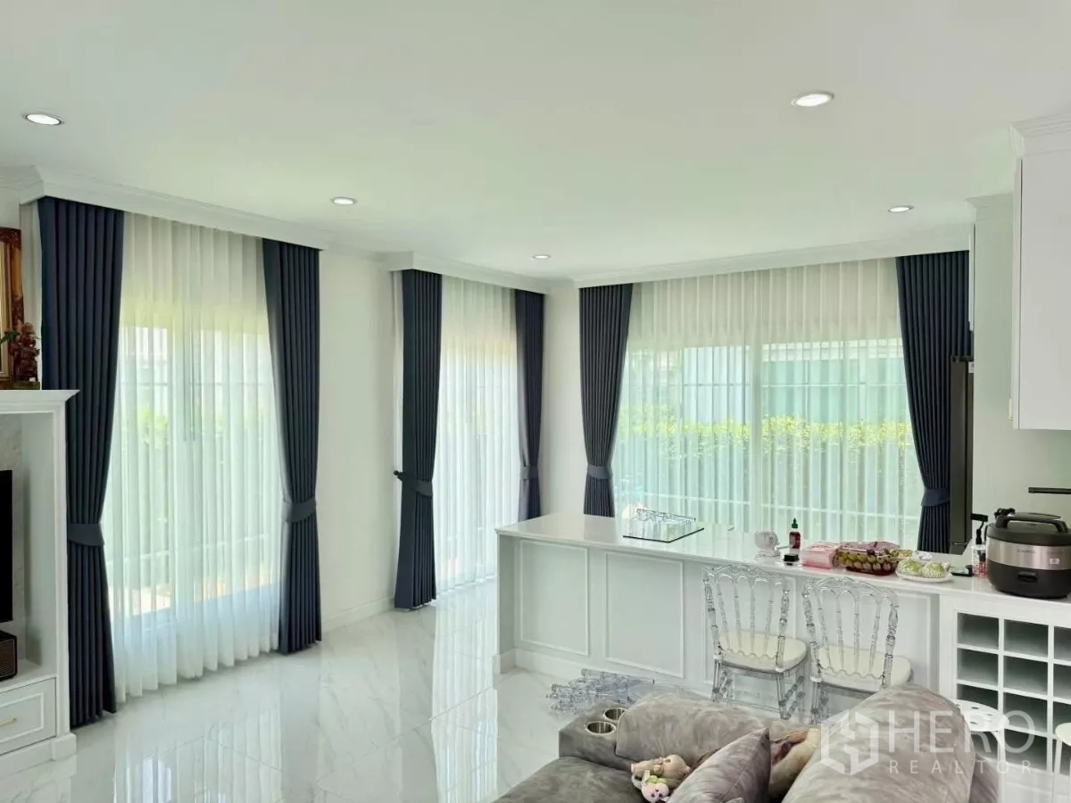 Detached House for rent in Bang Phli, Samut Prakan - Open-plan family area with breakfast bar, clear chairs, and floor-to-ceiling curtained windows.