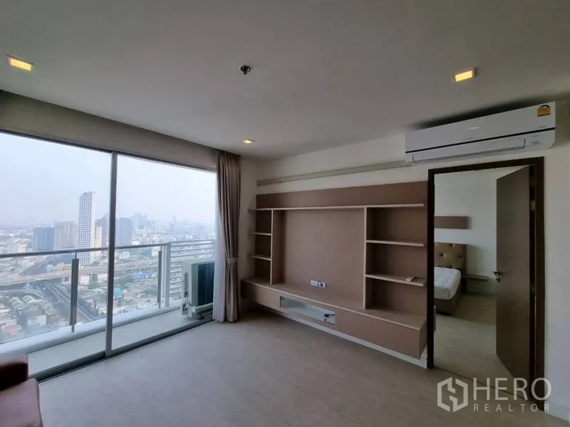 คอนโด ให้เช่าในWatthana, Bangkok - ห้องนั่งเล่นพร้อมผนังทีวีบิลต์อิน แอร์ และประตูกระจกออกระเบียงวิวเมือง พร้อมประตูไปห้องนอน