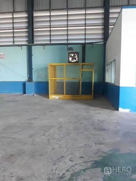 工厂 出租在Samut Prakan - 仓库一角设黄色安全围栏、通风风机及邻近办公室窗。