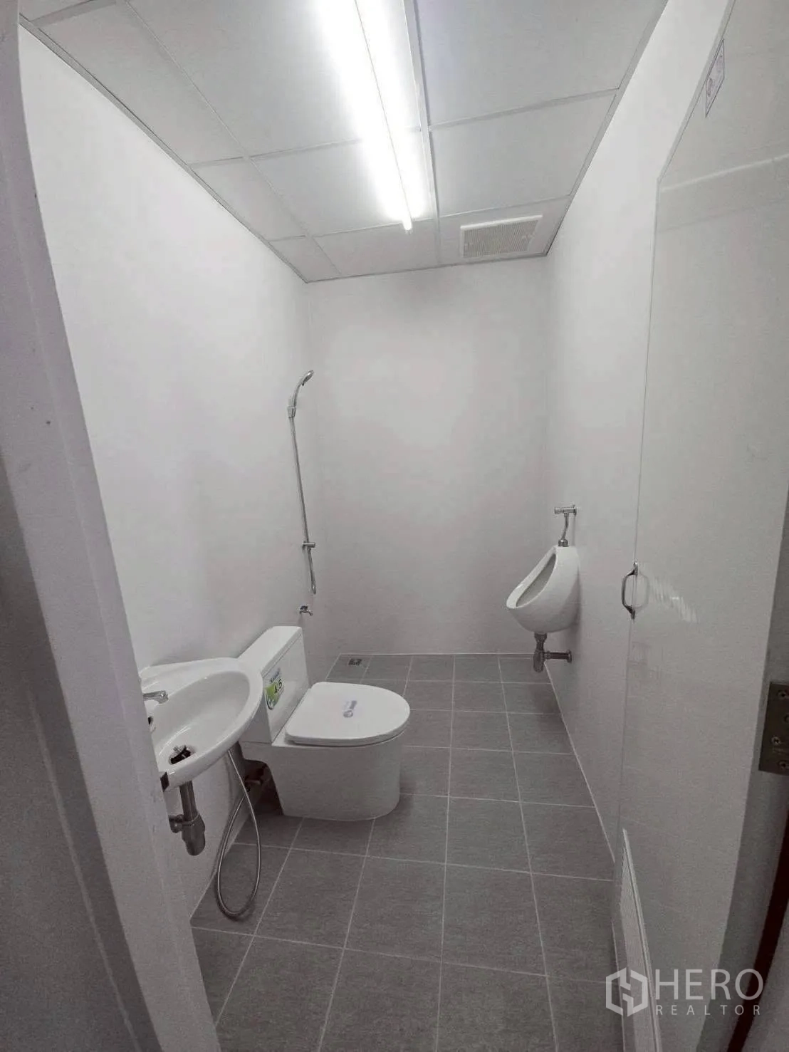 Warehouse for rent in Bang Phli, Samut Prakan - Restroom with sink, toilet, urinal, tiled floor, and overhead lighting.