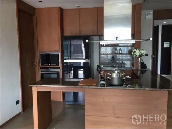 Condominium for rent in Watthana, Bangkok - Modern open kitchen with wood cabinetry, stone island, built-in oven and range hood.