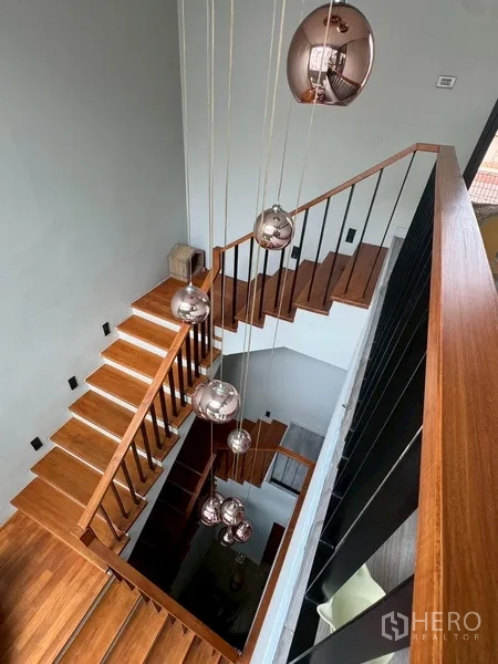 Semi-detached House for rent in Watthana, Bangkok - Stairwell with hanging copper pendant lights viewed from above.