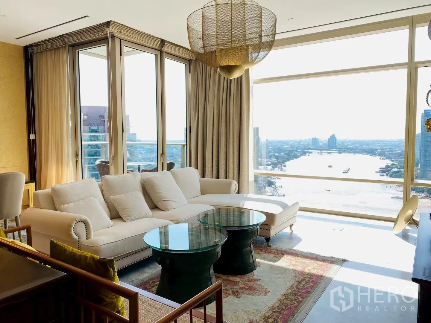 คอนโด for rent in Sathon, Bangkok - ห้องนั่งเล่นสว่างด้วยกระจกเต็มผนัง โซฟาสีครีม โต๊ะกระจก ระเบียง และวิวแม่น้ำกว้างไกล