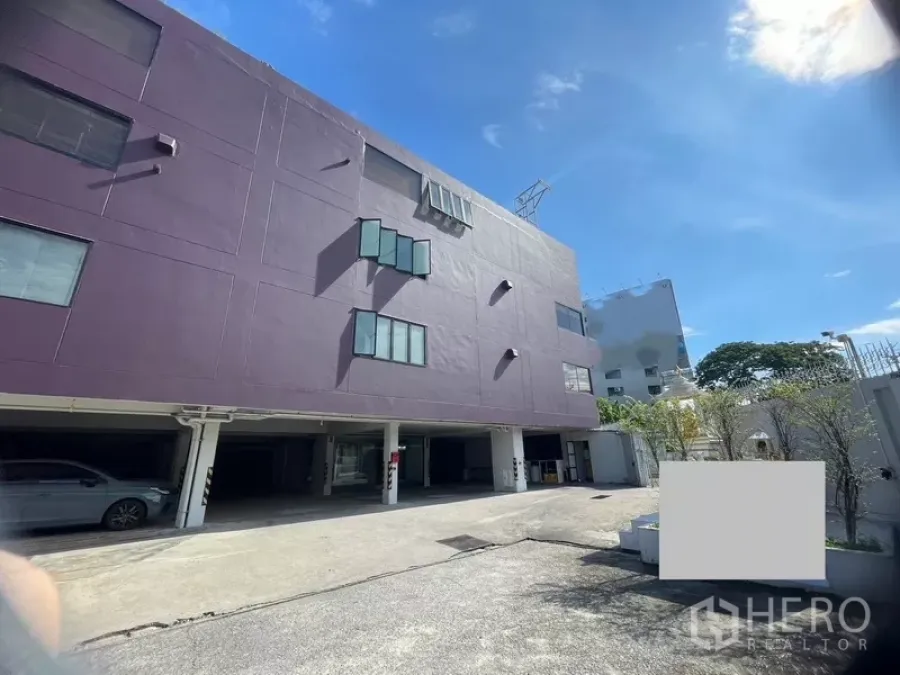 Office Space for rent or sale in Suan Luang, Bangkok - Five-storey office building in Suan Luang, Bangkok with covered parking and wide driveway under a blue sky.