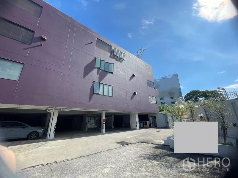 Office Space for rent or sale in Suan Luang, Bangkok - Five-storey office building in Suan Luang, Bangkok with covered parking and wide driveway under a blue sky.