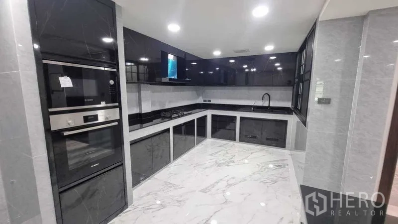 ทาวน์เฮาส์ ให้เช่าในKhlong Toei, Bangkok - ครัวบิวท์อินสไตล์โมเดิร์น ตู้สีดำ เตาอบ และพื้นลายหินอ่อน