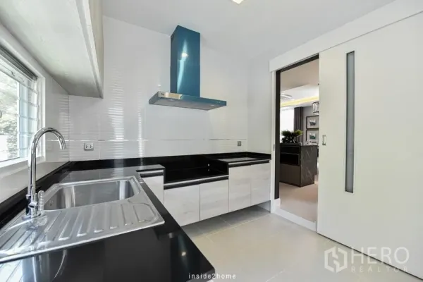 Detached House for rent in Samut Prakan - Separate Thai kitchen with black stone countertops, sink, window and sliding door.