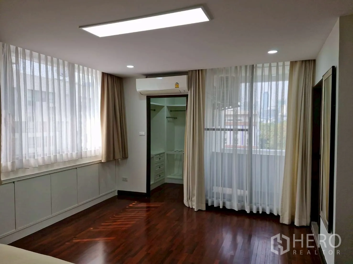 Condominium for rent in Khlong Toei, Bangkok - Bright bedroom with corner windows, air conditioner and entry to walk-in closet.