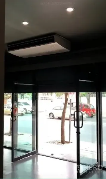 店屋 出租在Phra Khanong, Bangkok - 临街玻璃门头，双开玻璃门与吊顶柜式空调，面向人行道