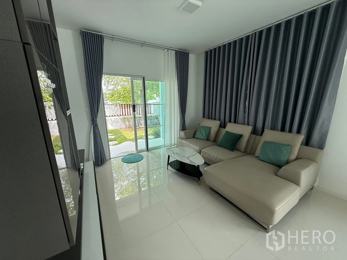 独栋房屋 for rent in Bang Phli, Samut Prakan - 客厅设推拉玻璃门通向花园，配落地窗帘。
