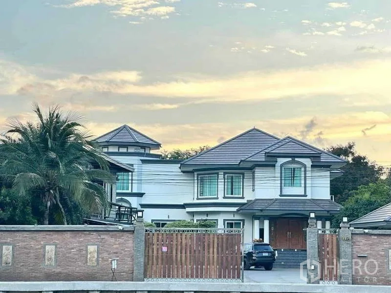 บ้าน ขายในKhlong Luang, Pathum Thani - บ้านเดี่ยวสองชั้นหลังคากระเบื้อง อยู่หลังกำแพงอิฐและประตูไม้ในบรรยากาศยามเย็นที่คลองหลวง