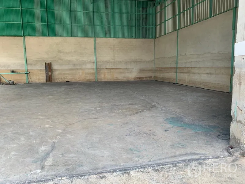 货栈 出租在Mueang Pathum Thani, Pathum Thani - 空置的仓库分区，混凝土地坪与绿色钢制墙面。