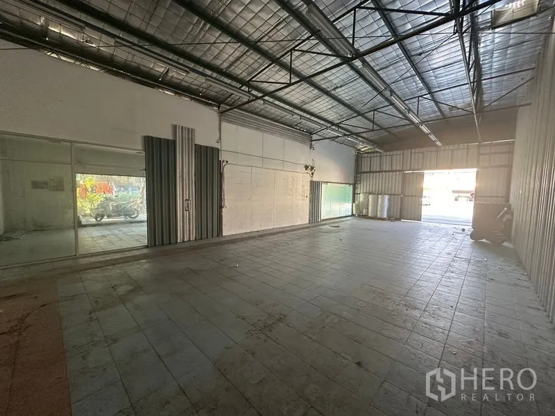 Warehouse for rent in Saphan Sung, Bangkok - Open-plan storage bay with insulated metal roof, fluorescent lighting and wide sliding doors.