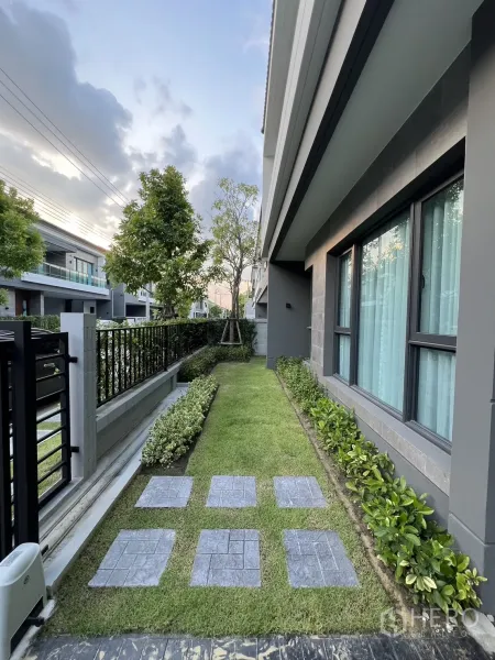 Detached House for rent or sale in Bang Phli, Samut Prakan - Side garden with stepping stones, neat hedges and large modern windows.