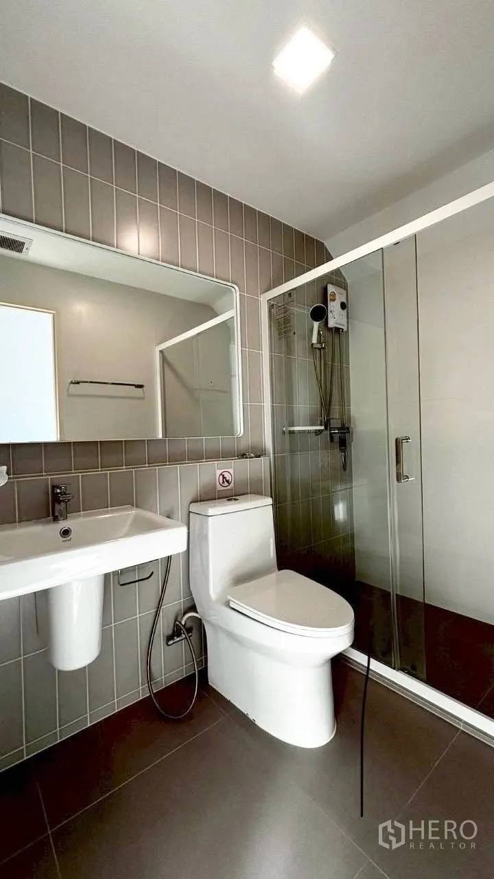 Townhouse for rent in Prawet, Bangkok - Modern bathroom with glass-enclosed shower, vanity sink and wall mirror.