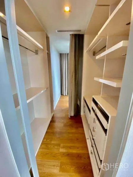 Condominium for rent in Sathon, Bangkok - Walk-in closet with white built-in shelving, drawers and wood floors.
