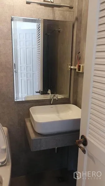 Townhouse for rent in Khlong Toei, Bangkok - Bathroom vanity with square basin and large mirror on gray tiles.