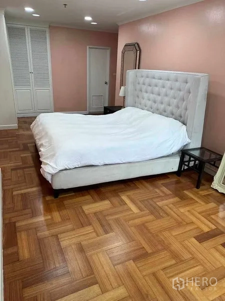 公寓 出售在Bangkok - 宽敞卧室，软包高靠背床，人字拼木地板与内置衣柜。