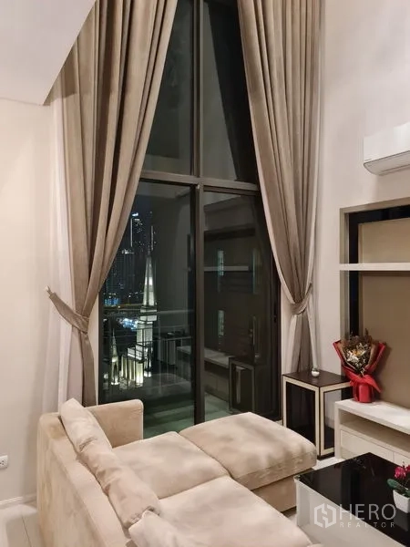 คอนโด ขายในRatchathewi, Bangkok - มุมนั่งเล่นยามค่ำพร้อมม่านสูง โซฟา และระเบียง