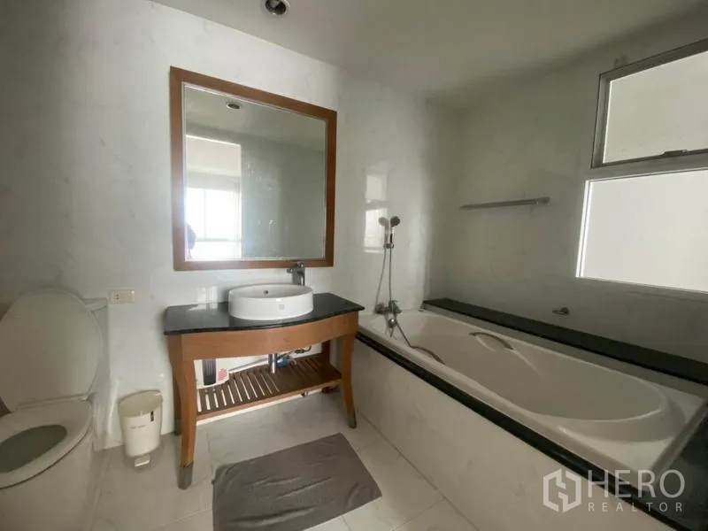 Condominium for rent in Watthana, Bangkok - Bathroom featuring a bathtub, vanity with round basin and mirror, and a toilet.