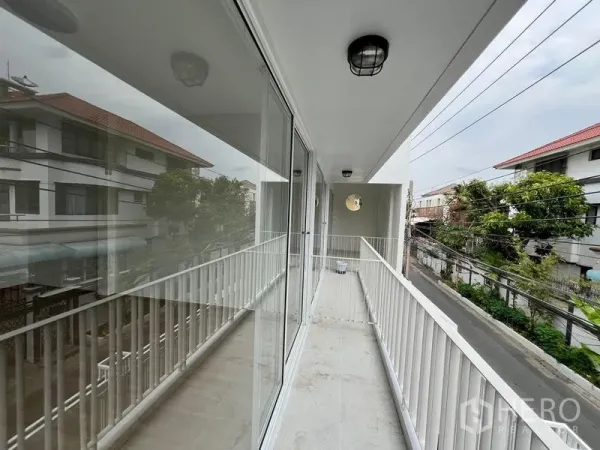 Home Office for rent in Huai Khwang, Bangkok - Covered second-floor balcony with glass sliding doors overlooking the neighborhood street.