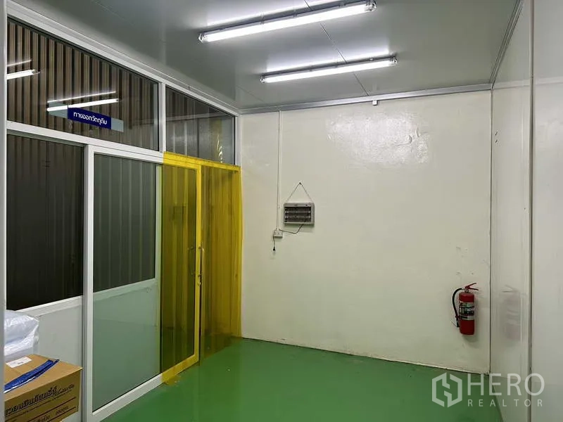Factory for rent in Khlong Luang, Pathum Thani - Materials exit area with yellow PVC strip curtains and green epoxy flooring.