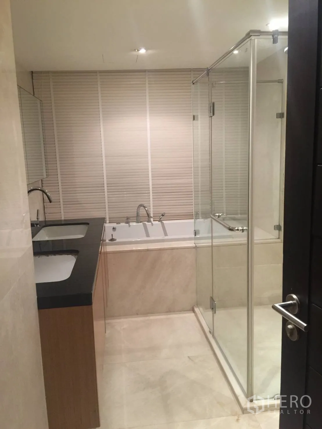 Condominium for rent in Watthana, Bangkok - Bathroom with double sinks, glass shower enclosure, and bathtub.