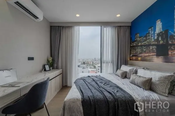 คอนโด ให้เช่าในPathum Wan, Bangkok - ห้องนอนมีโต๊ะทำงานบิวท์อิน หน้าต่างบานกว้าง มองเห็นวิวเมือง โทนผ้าปูสีเทา