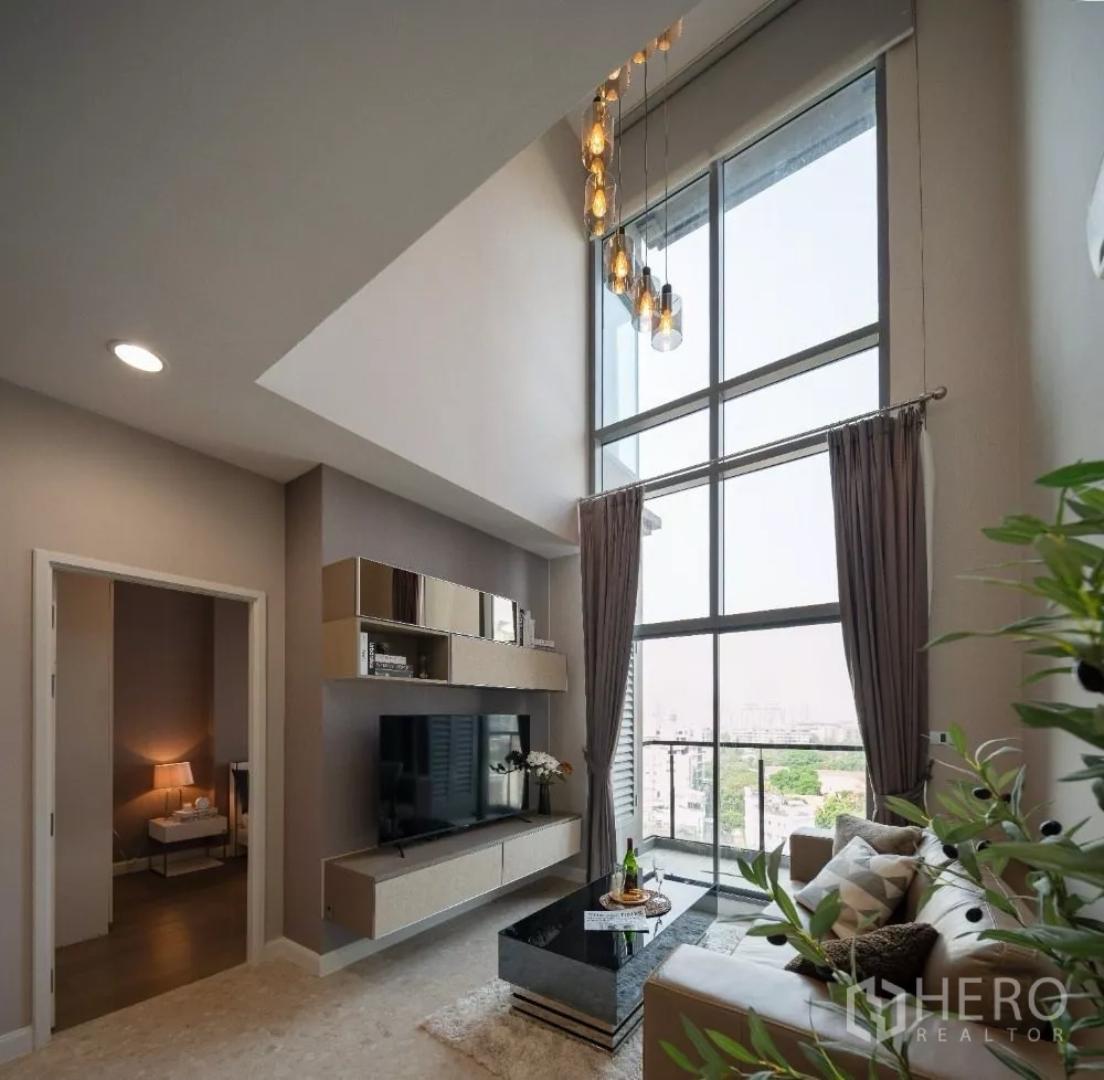 คอนโด ให้เช่าหรือขายในKhlong Toei, Bangkok - ห้องนั่งเล่นเพดานสูง ผนังทีวี หน้าต่างบานใหญ่ และระเบียงวิวเมือง