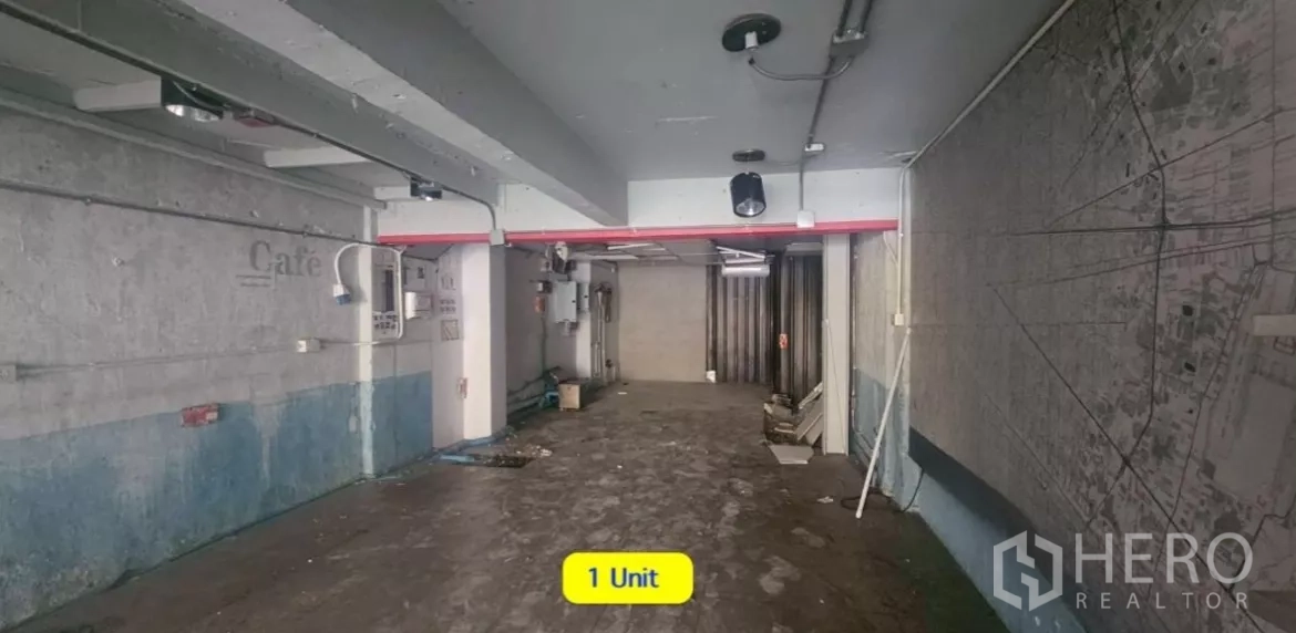 อาคารพาณิชย์ ให้เช่าในWatthana, Bangkok - พื้นที่ชั้นล่างโล่งของตึกแถว พื้นคอนกรีต เดินท่อลอย และมีประตูเหล็กม้วนด้านหลัง.