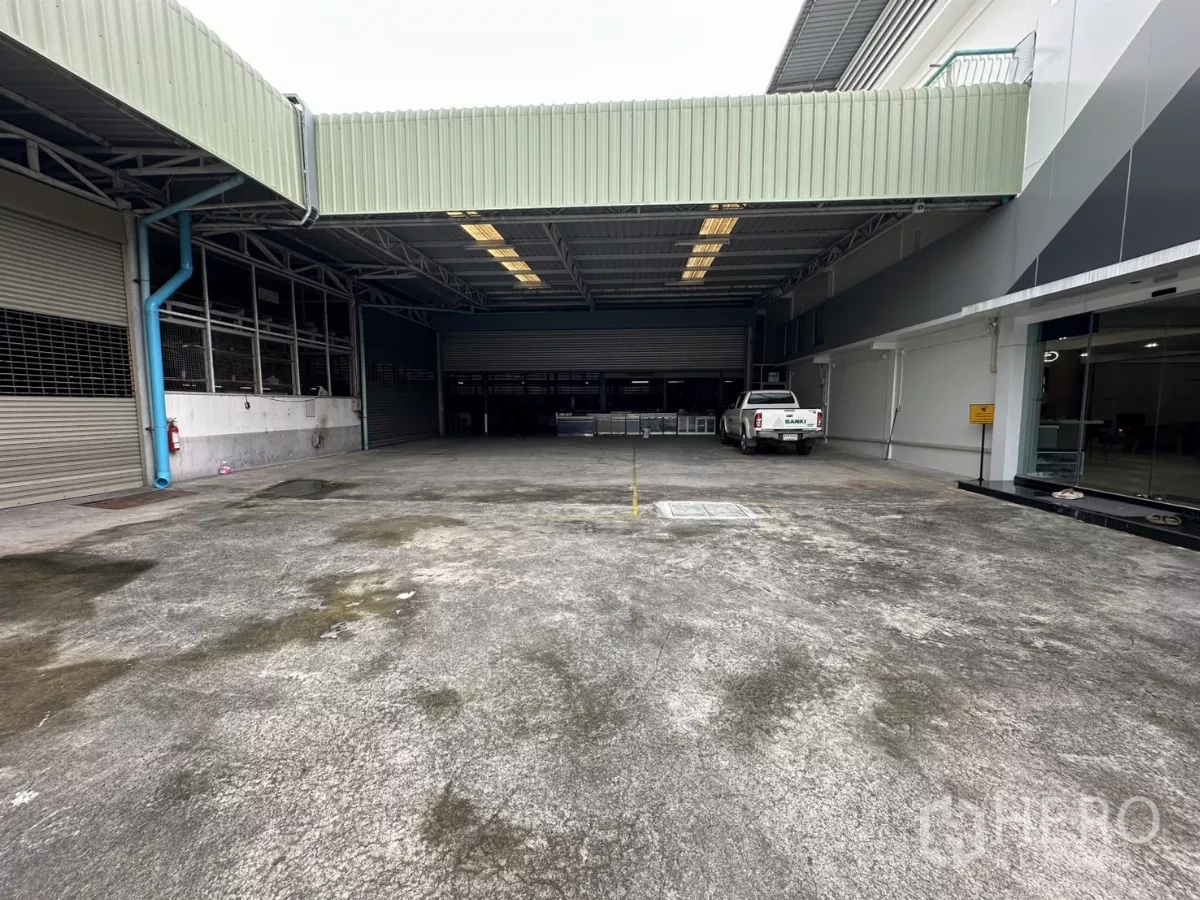 Warehouse for rent in Yan Nawa, Bangkok - Covered loading yard with roll-up doors and a pickup truck at a Bangkok warehouse.