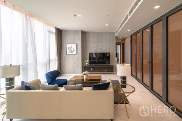 公寓 出租在Watthana, Bangkok - 沙发朝向电视墙，纹理墙面与折叠玻璃门。