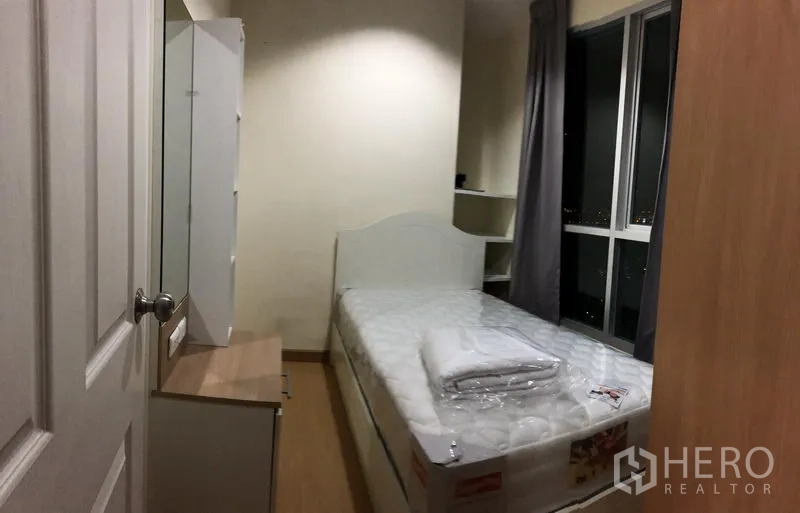 คอนโด ให้เช่าในWatthana, Bangkok - ห้องนอนรองมีเตียงเดี่ยว โต๊ะเครื่องแป้ง และหน้าต่างเห็นวิวเมืองยามค่ำ