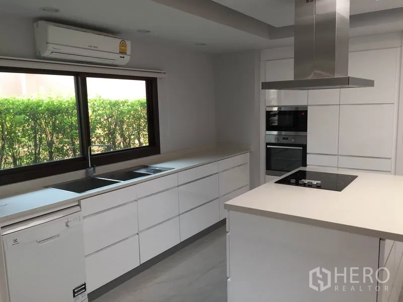 Detached House for rent in Sathon, Bangkok - Modern white kitchen with island, built-in oven, cooktop and range hood