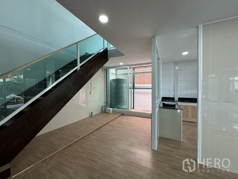 Townhouse for sale in Bueng Kum, Bangkok - Under-stair area by the kitchen with glass railing and storage tank near sliding doors.