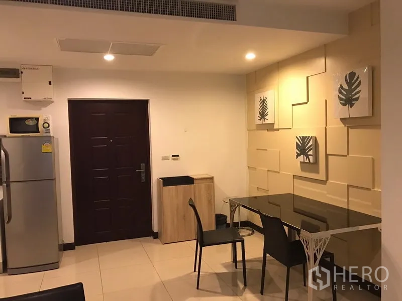 公寓 出租在Watthana, Bangkok - 用餐角，玻璃餐桌、装饰墙画与入户门下方筒灯