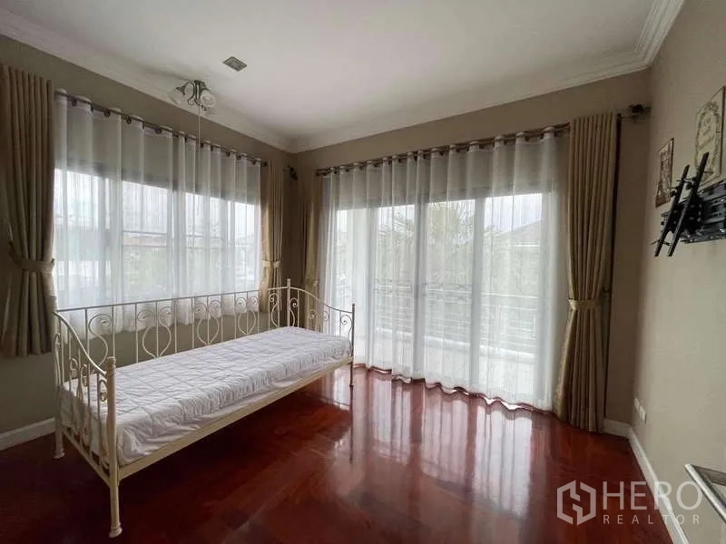 独立式住宅 出租在Mueang Nonthaburi, Nonthaburi - 采光充足的房间，日间床、木地板与落地玻璃门通阳台。