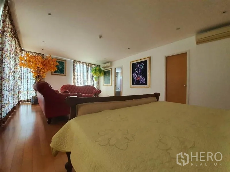 คอนโด ขายในWatthana, Bangkok - มุมพักผ่อนในห้องนอน ผ้าม่านลายดอก โซฟาสีแดง และพื้นไม้