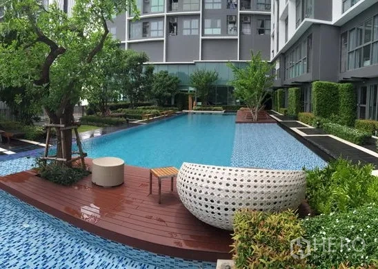 公寓 出租在Phra Khanong, Bangkok - 现代公寓园区内的度假风泳池、木质甲板与绿化。