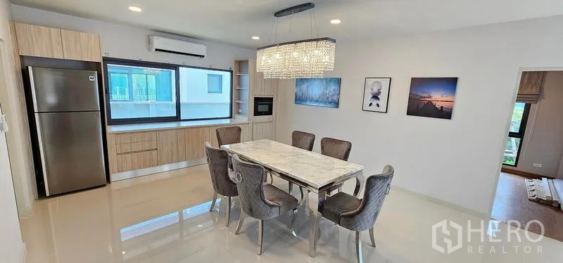 Detached House for rent in Bang Phli, Samut Prakan - Dining kitchen with marble-top table, crystal chandelier, built-in cabinetry and a wide window.