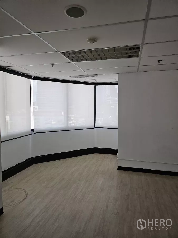 办公空间 出租在Watthana, Bangkok - 明亮的转角办公室，环绕窗配卷帘，木纹地板与格栅吊顶。