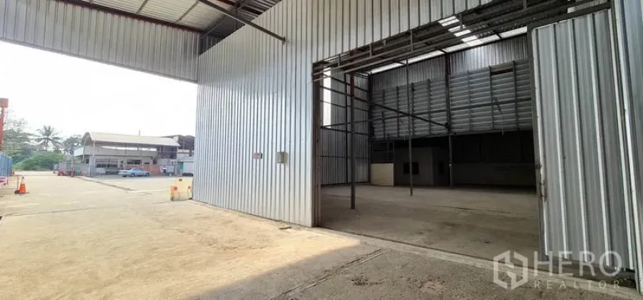 Warehouse for rent in Pak Kret, Nonthaburi - Wide metal-clad warehouse with large sliding door and open yard in Pak Kret, Nonthaburi.
