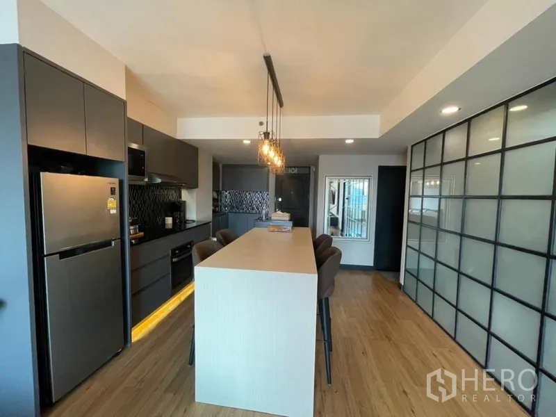Condominium for sale in Chatuchak, Bangkok - Full kitchen with tall fridge, built-in oven and a long breakfast island with seating.