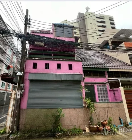 店屋 出租在Watthana, Bangkok - 瓦他那区粉色多层店屋外观，临街卷闸门与瓦屋顶。