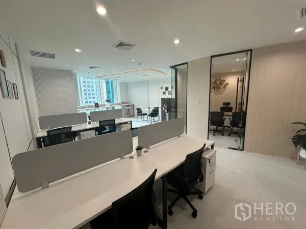 Office Space for rent - Open‑plan workstations with partitions facing glass‑walled office and window bar.