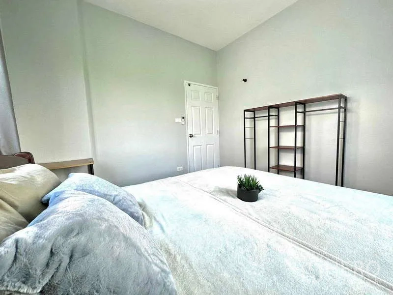 บ้าน ให้เช่าในLat Krabang, Bangkok - มุมห้องนอนเห็นเตียง ประตู และชั้นเหล็กเปิดโล่งบนผนังสีอ่อน