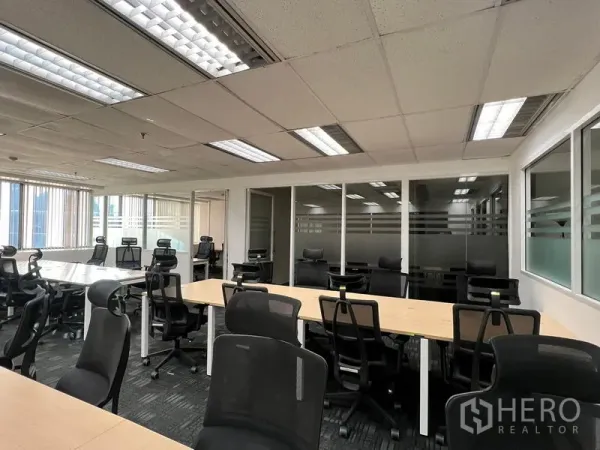 Office Space for rent in Khlong Toei, Bangkok - Workstations with ergonomic chairs facing glass-partitioned offices beneath grid ceiling lights.