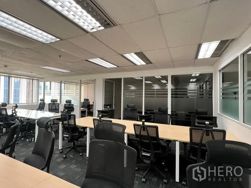 Office Space for rent in Khlong Toei, Bangkok - Workstations with ergonomic chairs facing glass-partitioned offices beneath grid ceiling lights.
