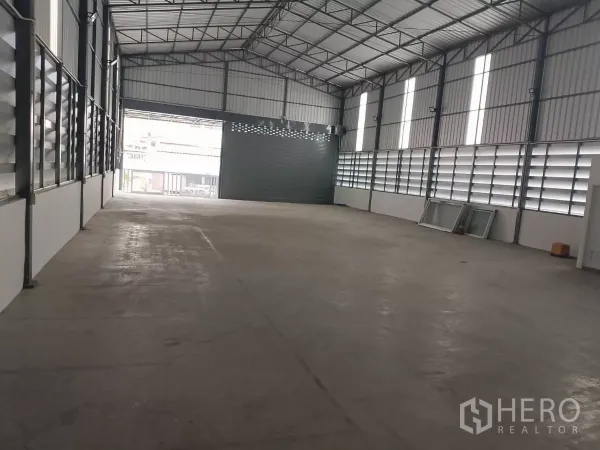 Warehouse for rent in Huai Khwang, Bangkok - Spacious warehouse interior with high gable roof and louvered windows, view to front door.