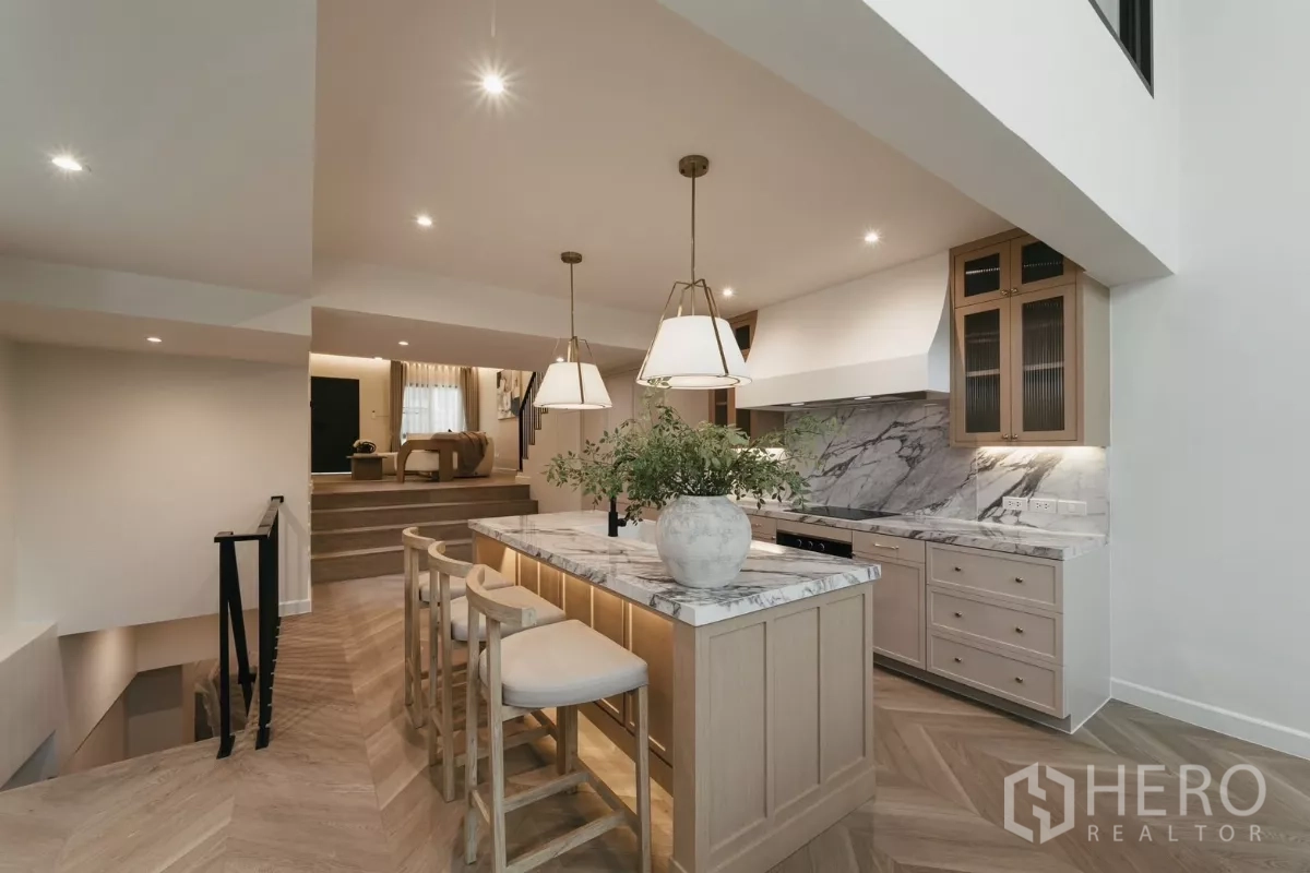 联排别墅 出租在Watthana, Bangkok - 开放式大理石中岛厨房，吊灯与错层客厅相连。